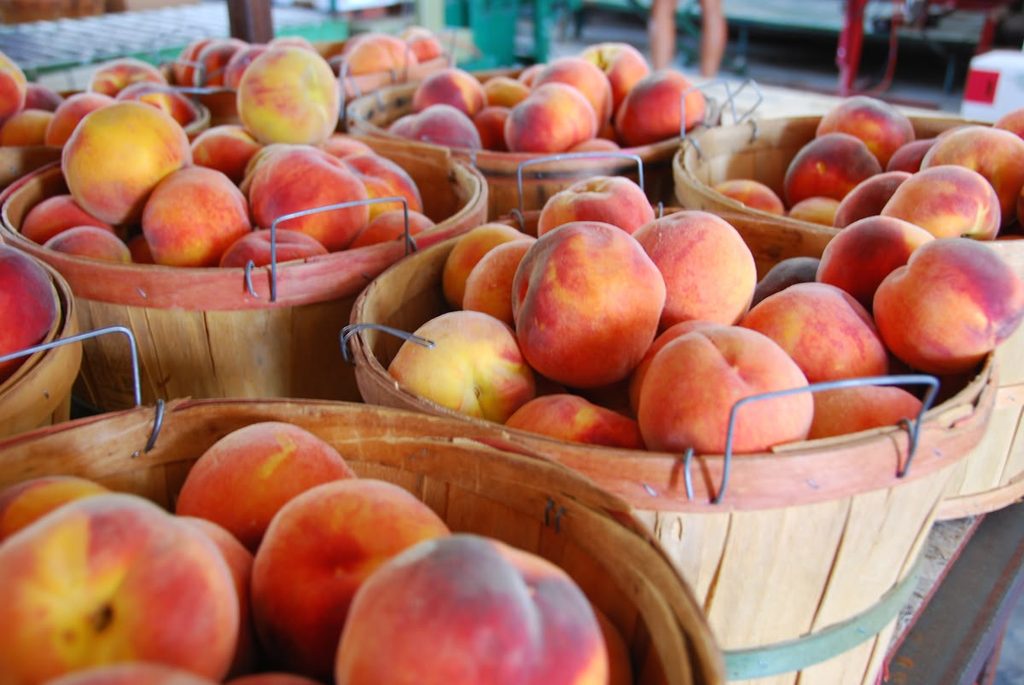 Fresh Palisade peaches displayed in wooden baskets at a farmers market in Colorado.